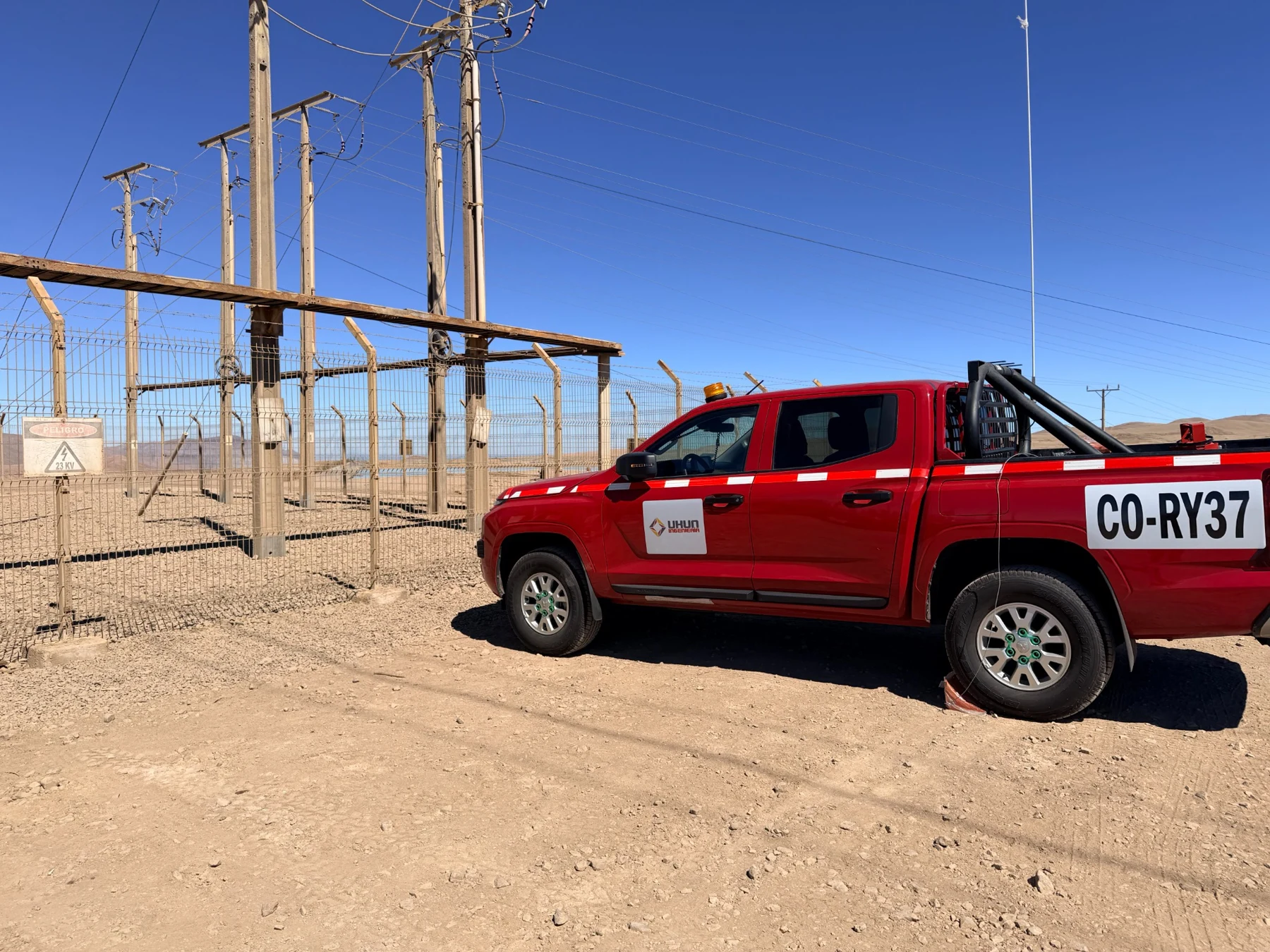 Camioneta UKUN junto a instalaciones eléctricas de 23 kV en un entorno desértico